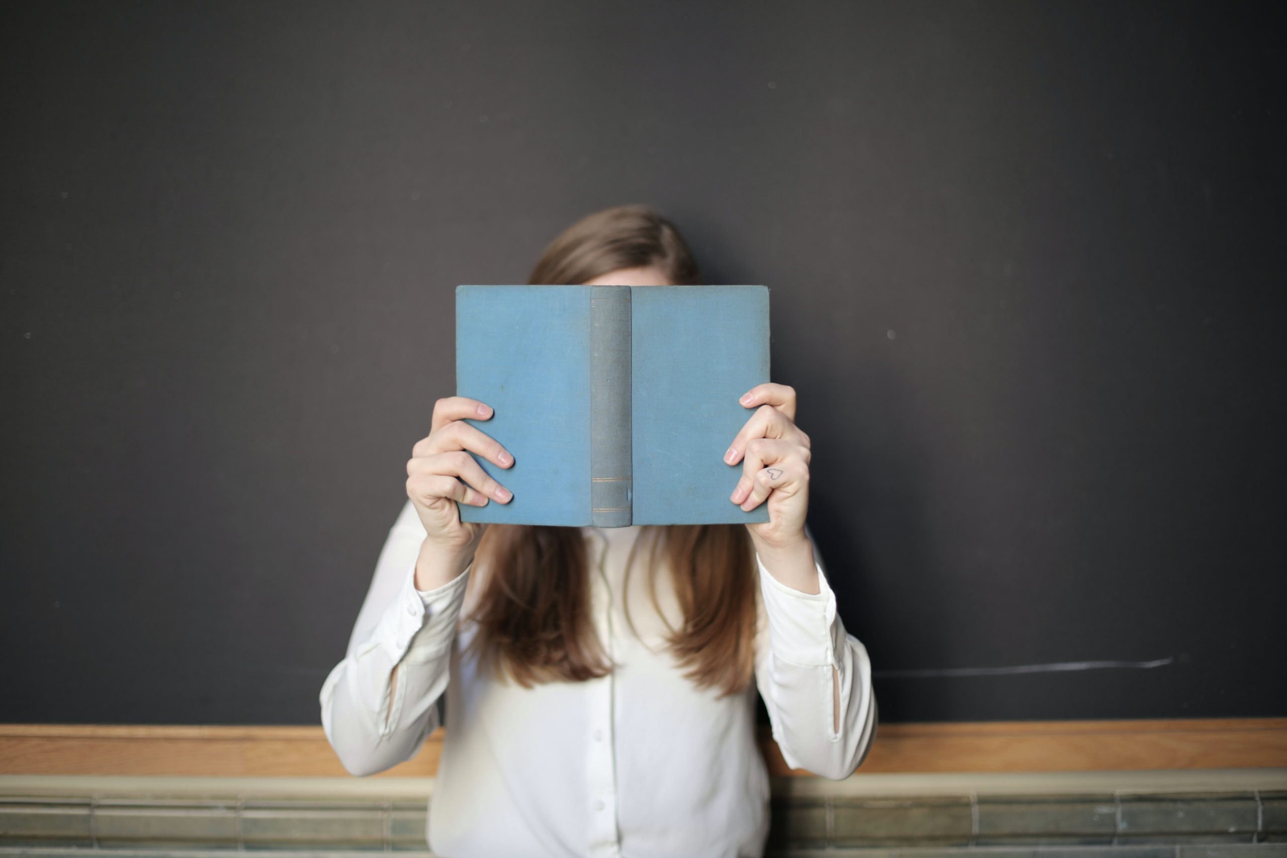 Une femme se cache derrière un livre